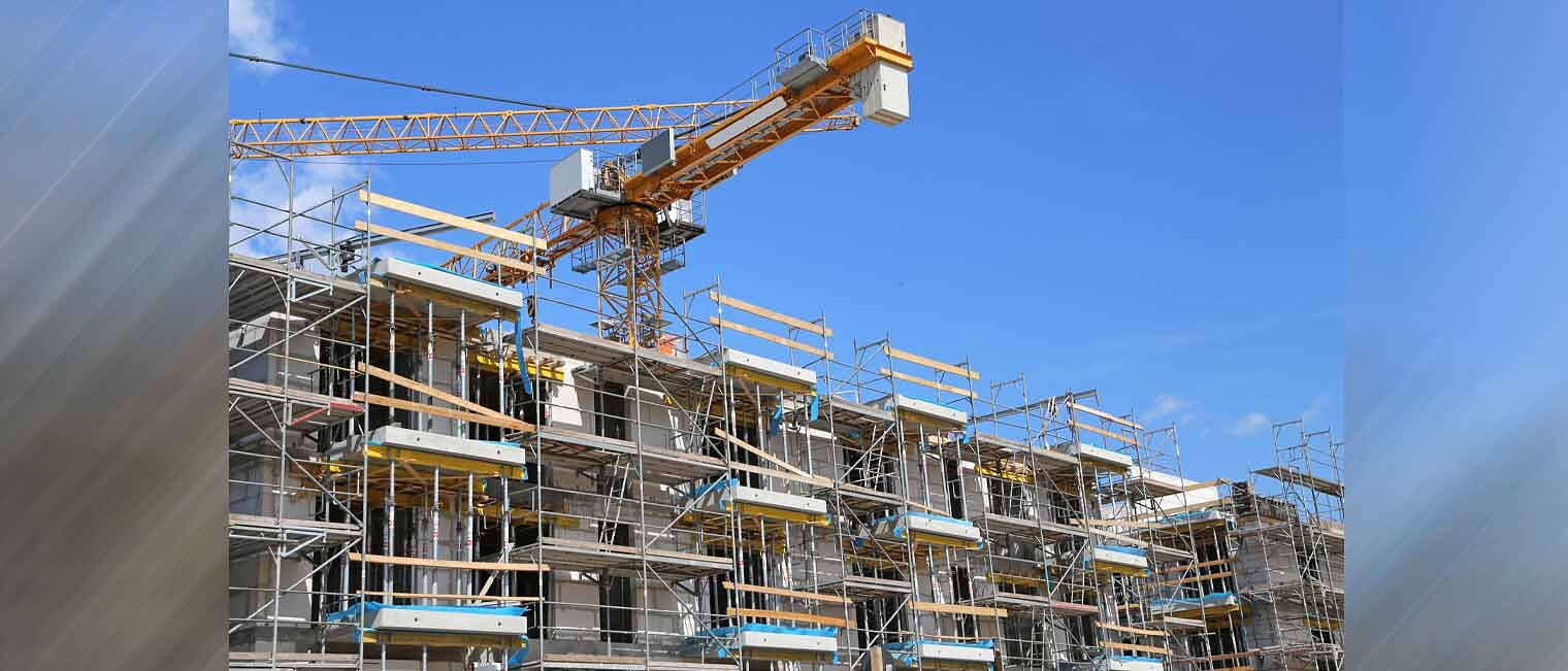 Baustelle | Kurzarbeitergeld Baubranche Mehrfamilienhaus Rohbau mit Gerüst und Baukran dahinter