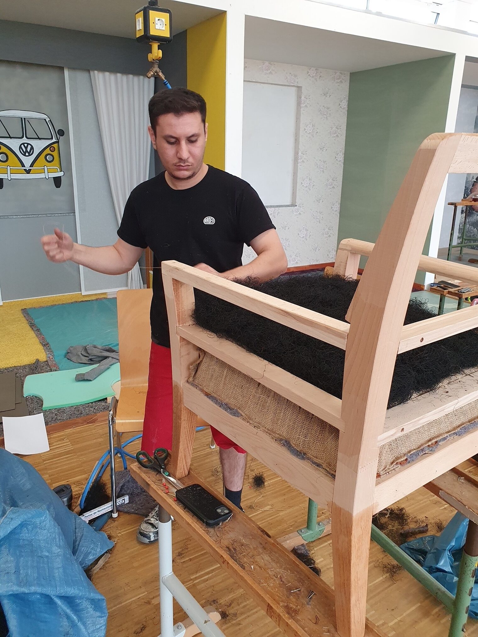 Mohamad Hanafi bei seiner Arbeit an einem Holzsessel. Er blickt konzentriert auf seine Arbeit