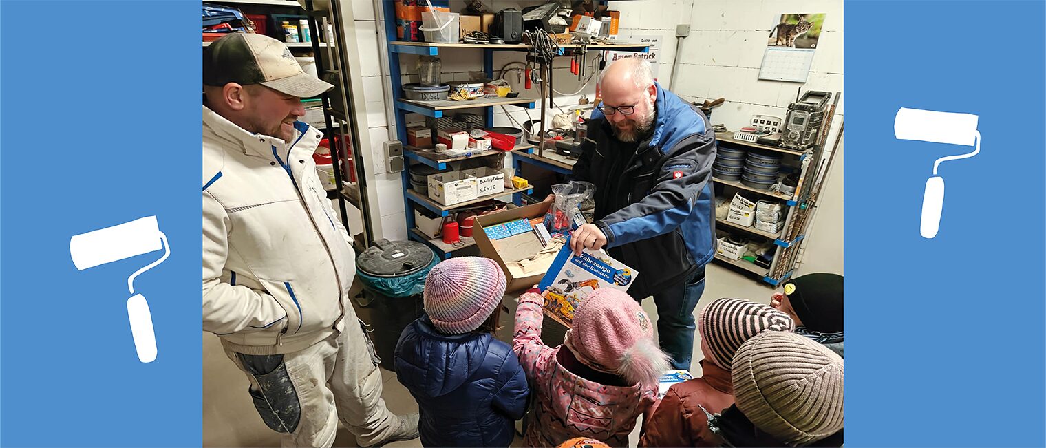 Kinder und Erwachsene packen im Malerbetrieb Spiele und Geschenke aus. 