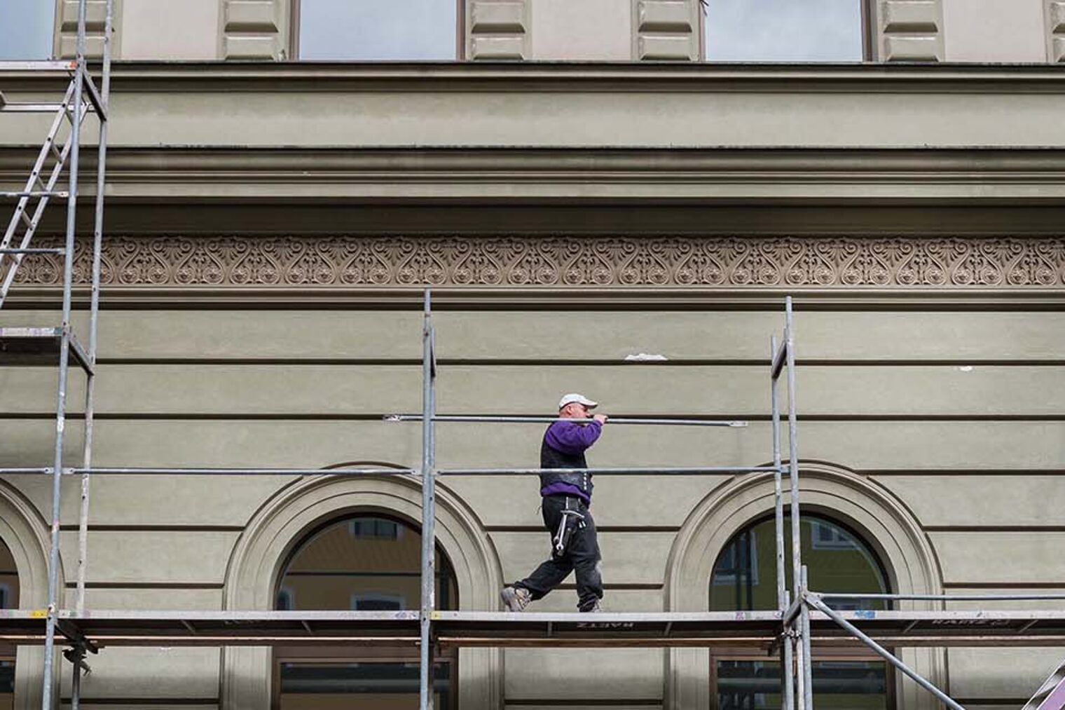 Totale von Gerüst an Gebäude mit einem darauf laufenden Gerüstbauer